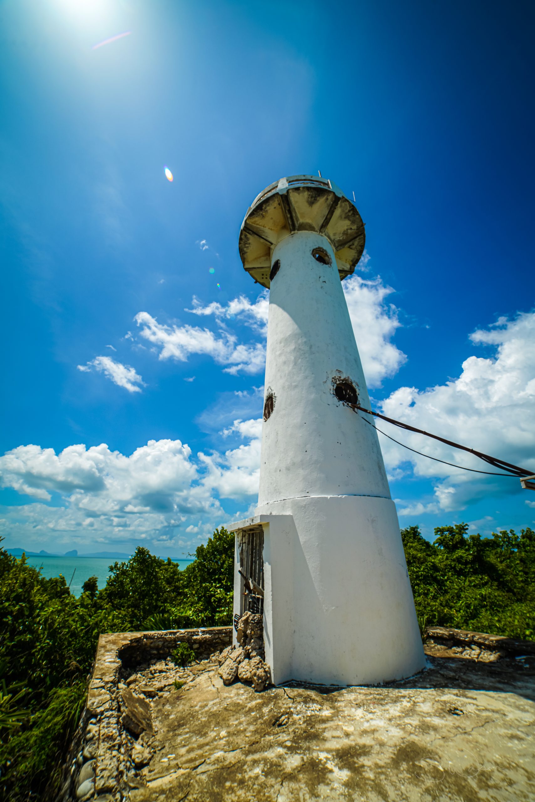 White light house on the shore with beautiful blue sky with clouds